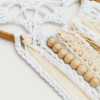 Detalle Mandala Átomo Blanco-Beige Detalle del mandala artesanal blanco y beige con crochet, cintas de encaje y cuentas de madera clara.
