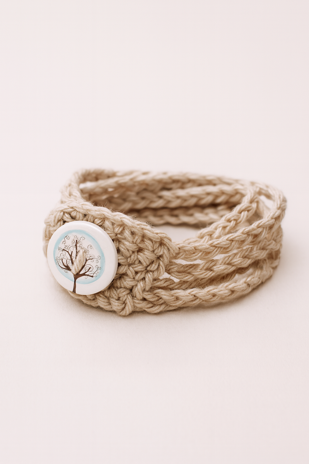 Pulsera Árbol – Hecha a mano con botón de madera y cinco trenzas beige Pulsera artesanal beige de cinco cadenetas con botón de madera decorado con un árbol.