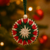 bola_estrella_invierno_verde_roja_contexto Adorno navideño de crochet hecho a mano en forma de bola con diseño estrellado en tonos rojo, verde y beige, sostenido por un cordón verde con cuenta de madera.