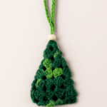 Mini Árbol de Navidad de Crochet en tonos verdes | Adorno artesanal con detalle de madera – LinkArt Adorno artesanal en forma de árbol de Navidad tejido a crochet con granny square en tonos verdes y detalle de bolita de madera, sobre fondo claro.