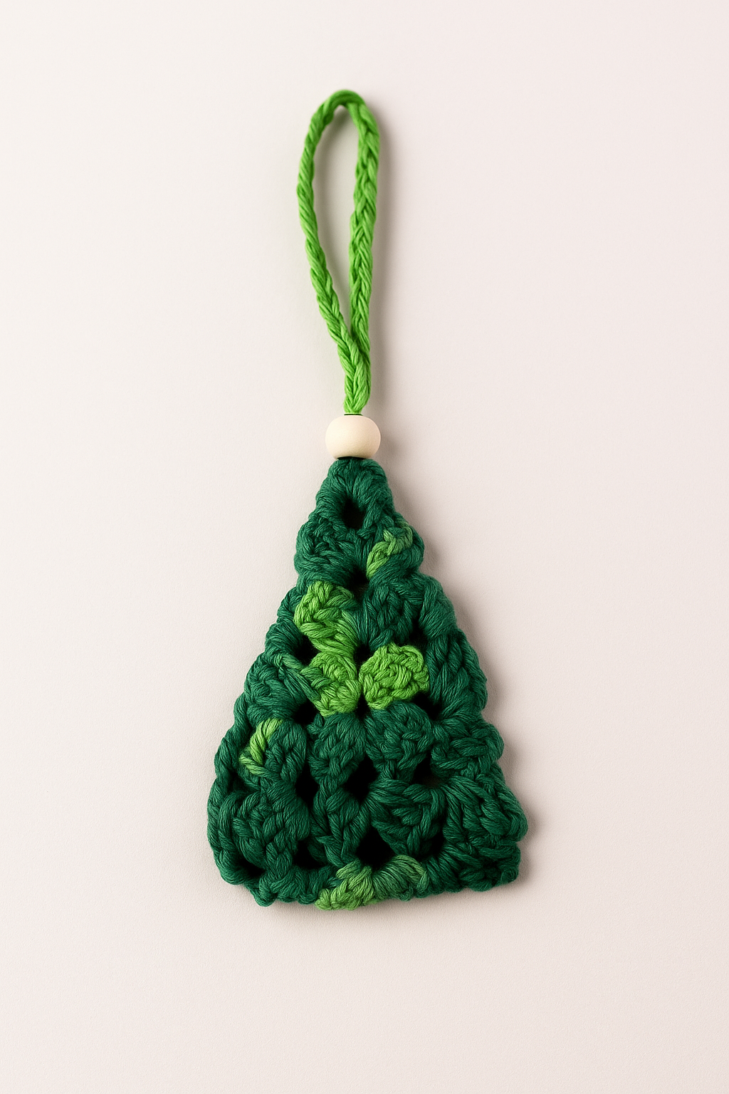 Mini Árbol de Navidad de Crochet en tonos verdes | Adorno artesanal con detalle de madera – LinkArt Adorno artesanal en forma de árbol de Navidad tejido a crochet con granny square en tonos verdes y detalle de bolita de madera, sobre fondo claro.