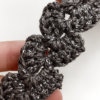 Detalle del tejido en crochet de una pulsera artesanal gris con punto floral