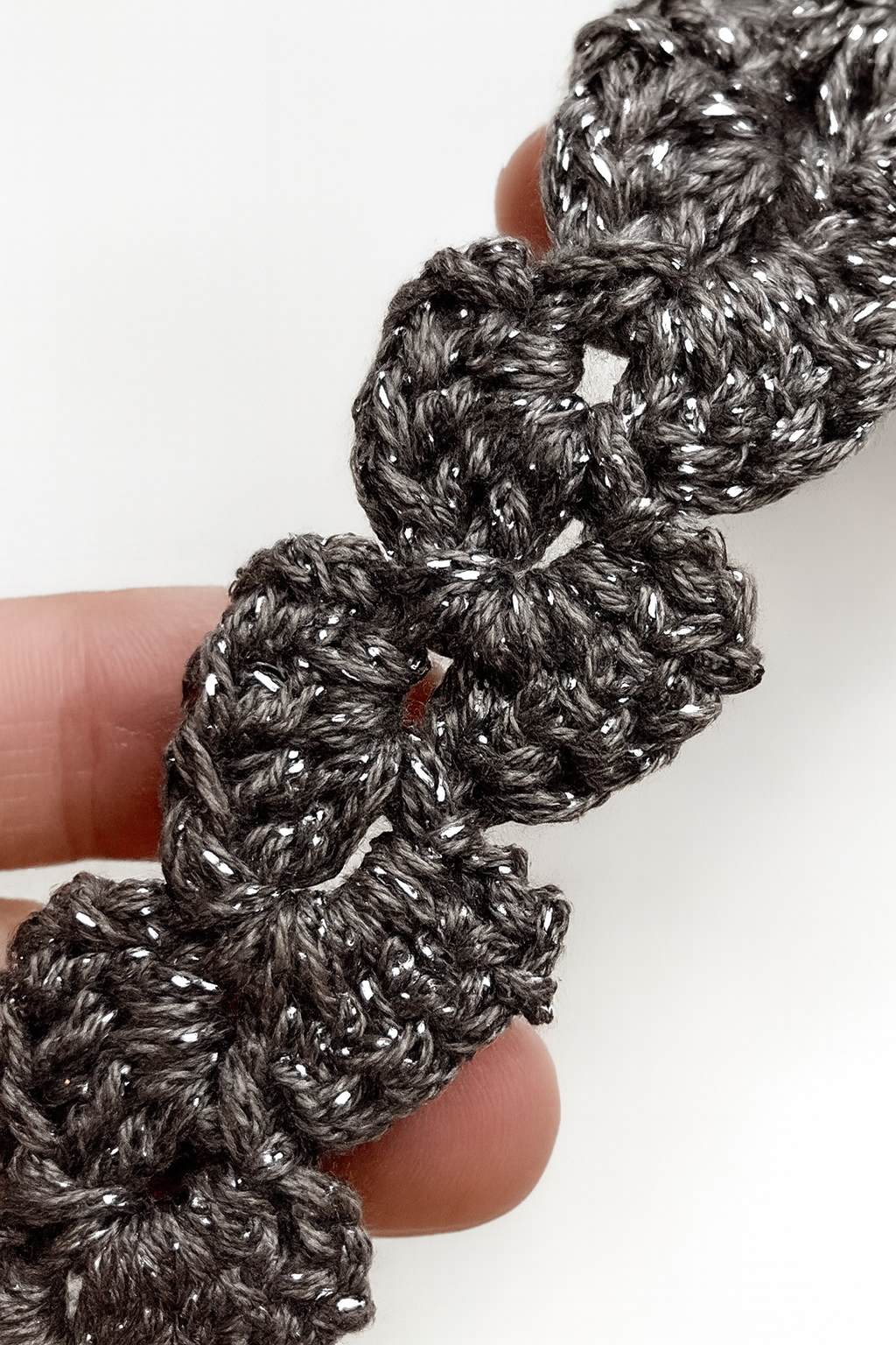 Detalle del tejido en crochet de una pulsera artesanal gris con punto floral