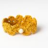 Pulsera artesanal de crochet mostaza tejida a mano con motivo floral y cierre de botón