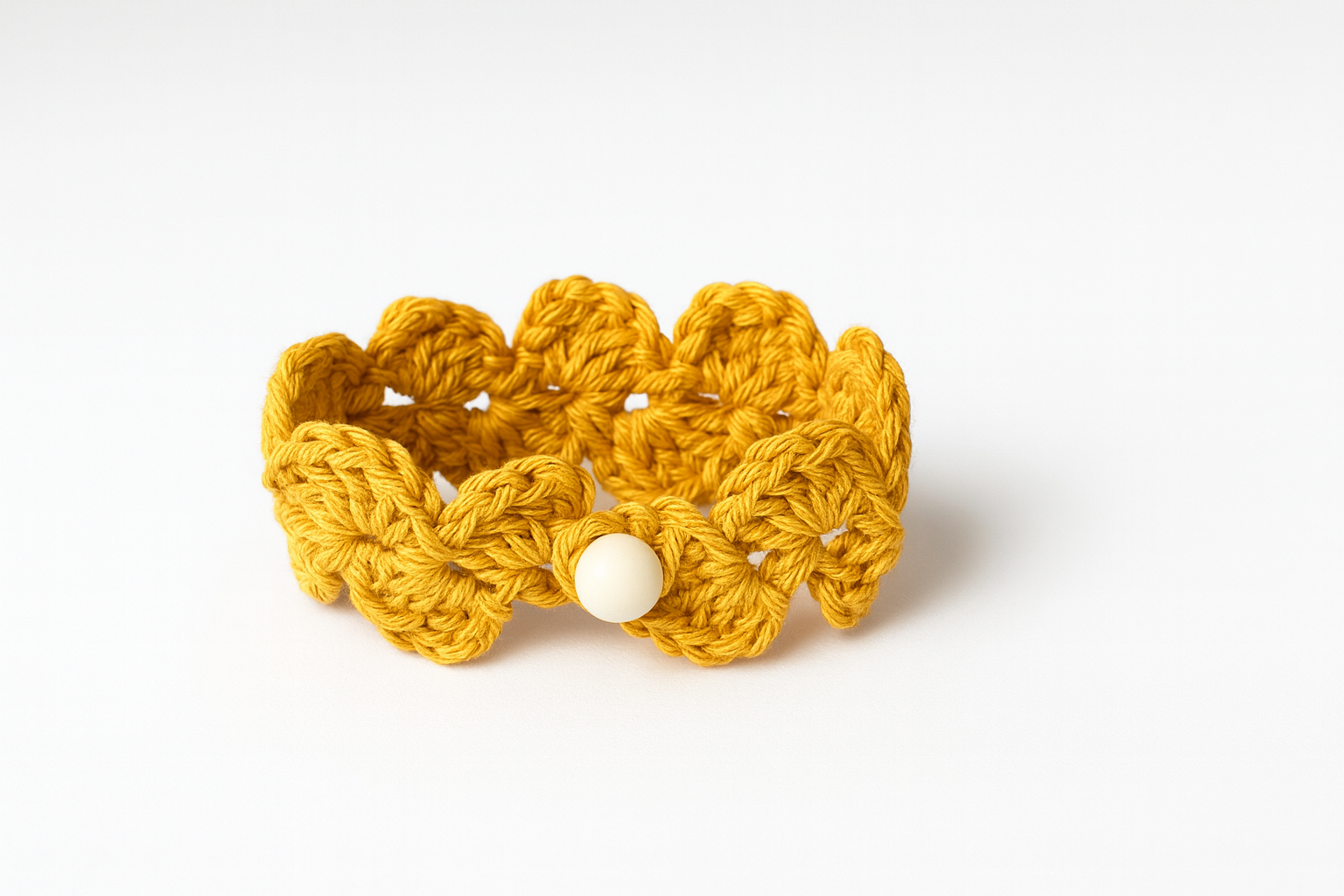 Pulsera artesanal de crochet mostaza tejida a mano con motivo floral y cierre de botón