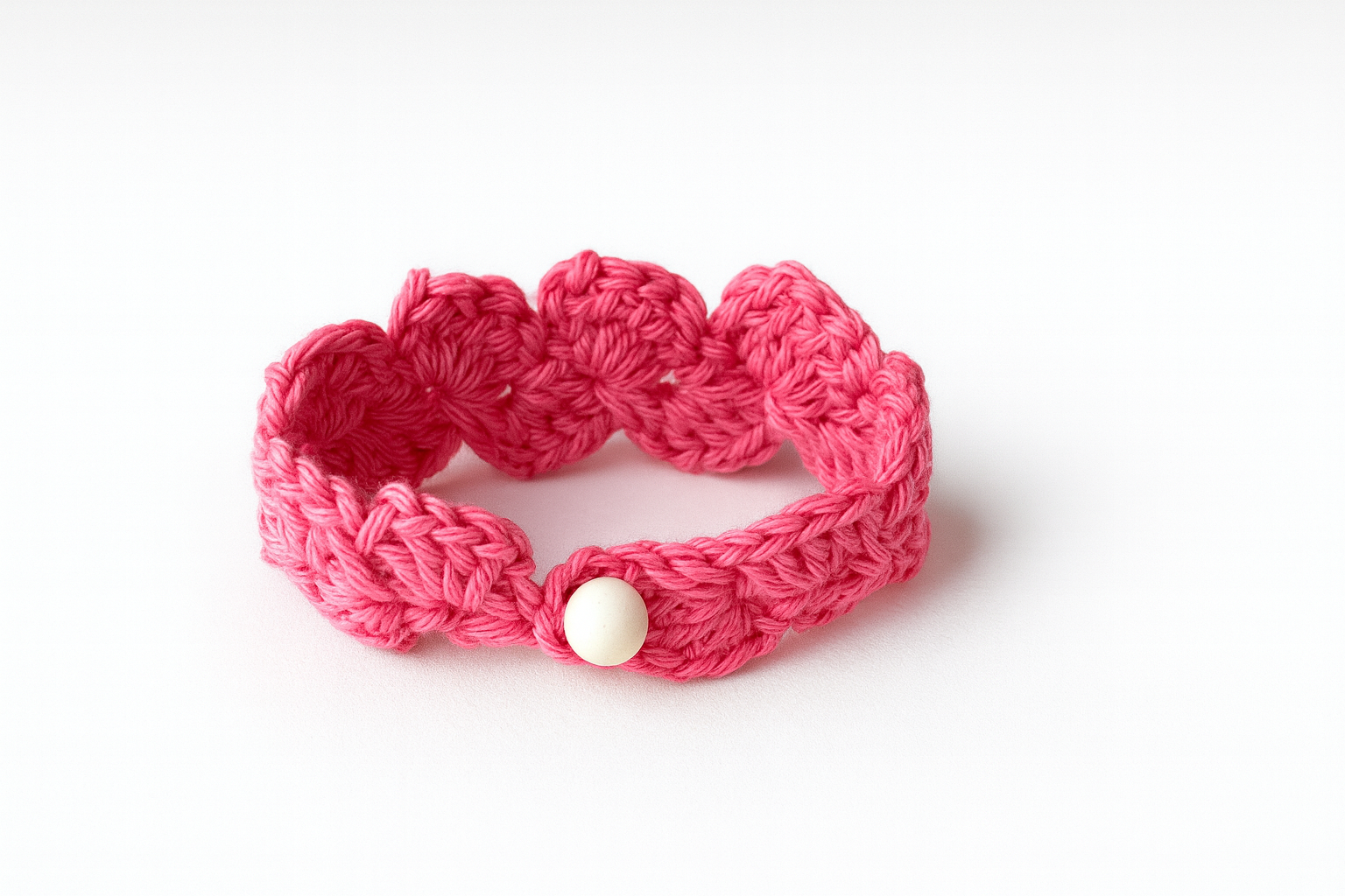 Pulsera artesanal de crochet rosa tejida a mano con motivo floral y cierre de botón