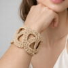Pulsera Unión tejida a crochet en color dorado, mostrada en la muñeca sobre fondo blanco.