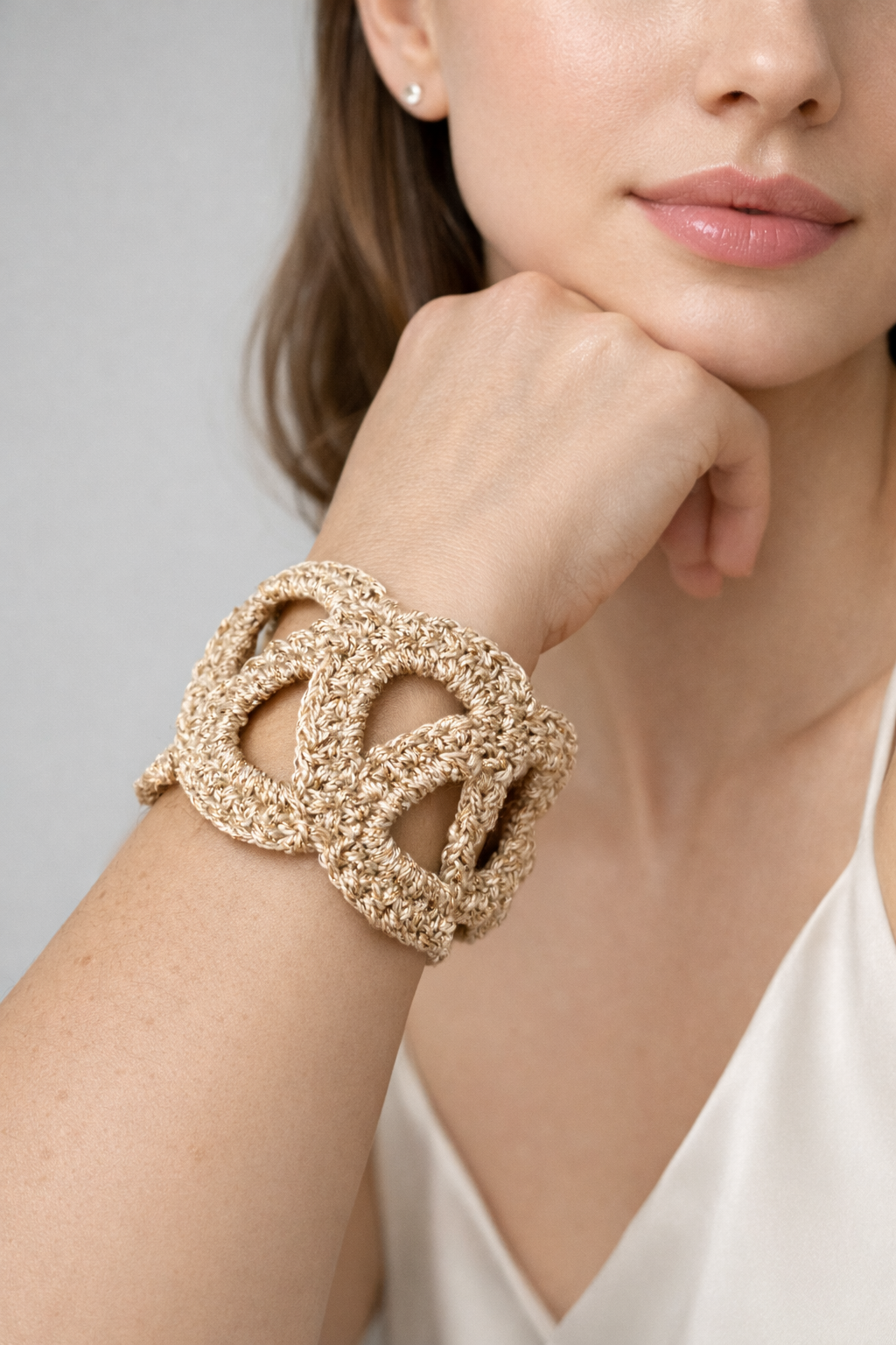 Pulsera Unión tejida a crochet en color dorado, mostrada en la muñeca sobre fondo blanco.