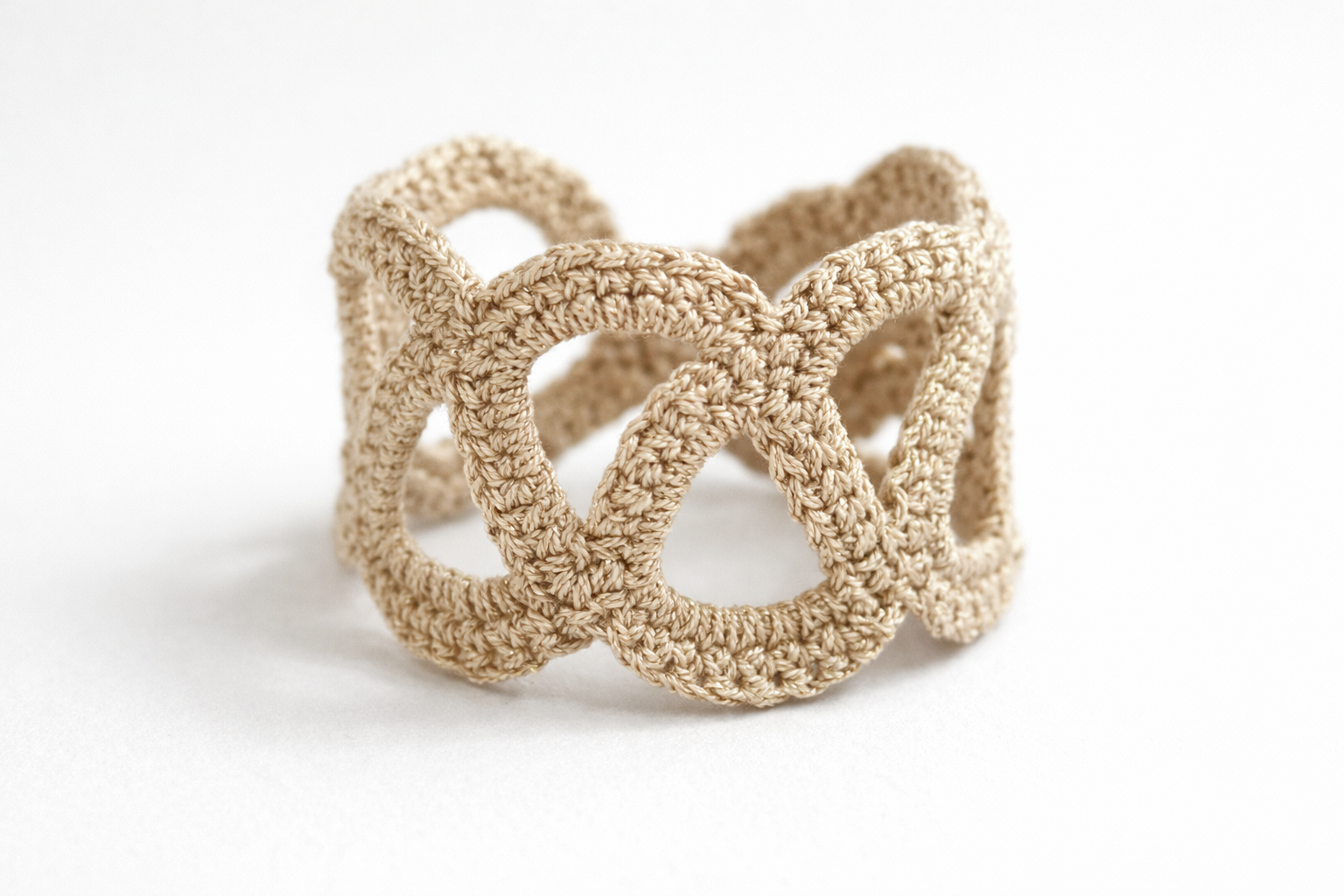 Pulsera Unión de crochet en color dorado fotografiada sola sobre fondo claro.